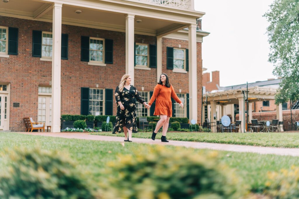 Two women walking while holding hands at UNC Chapel Hill Campus